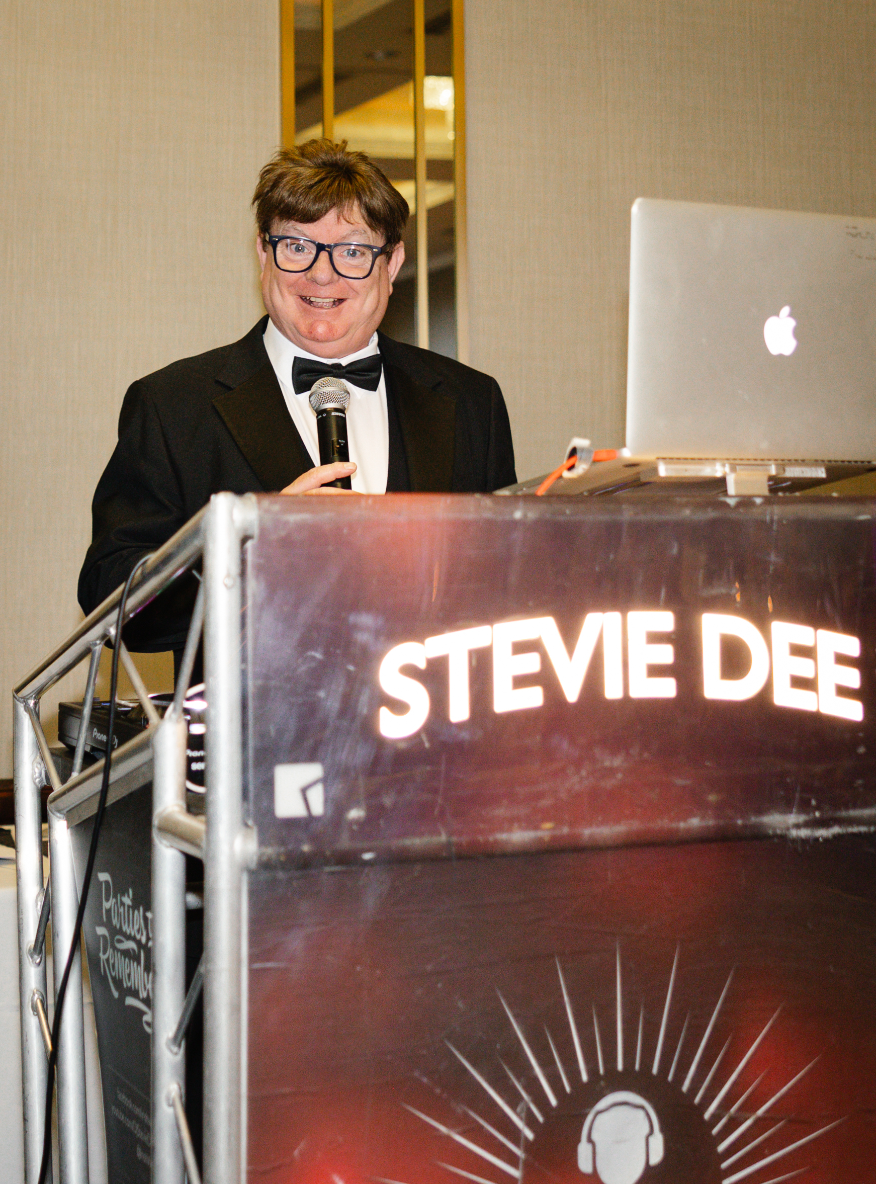DJ performing behind a lit Stevie Dee booth at a wedding