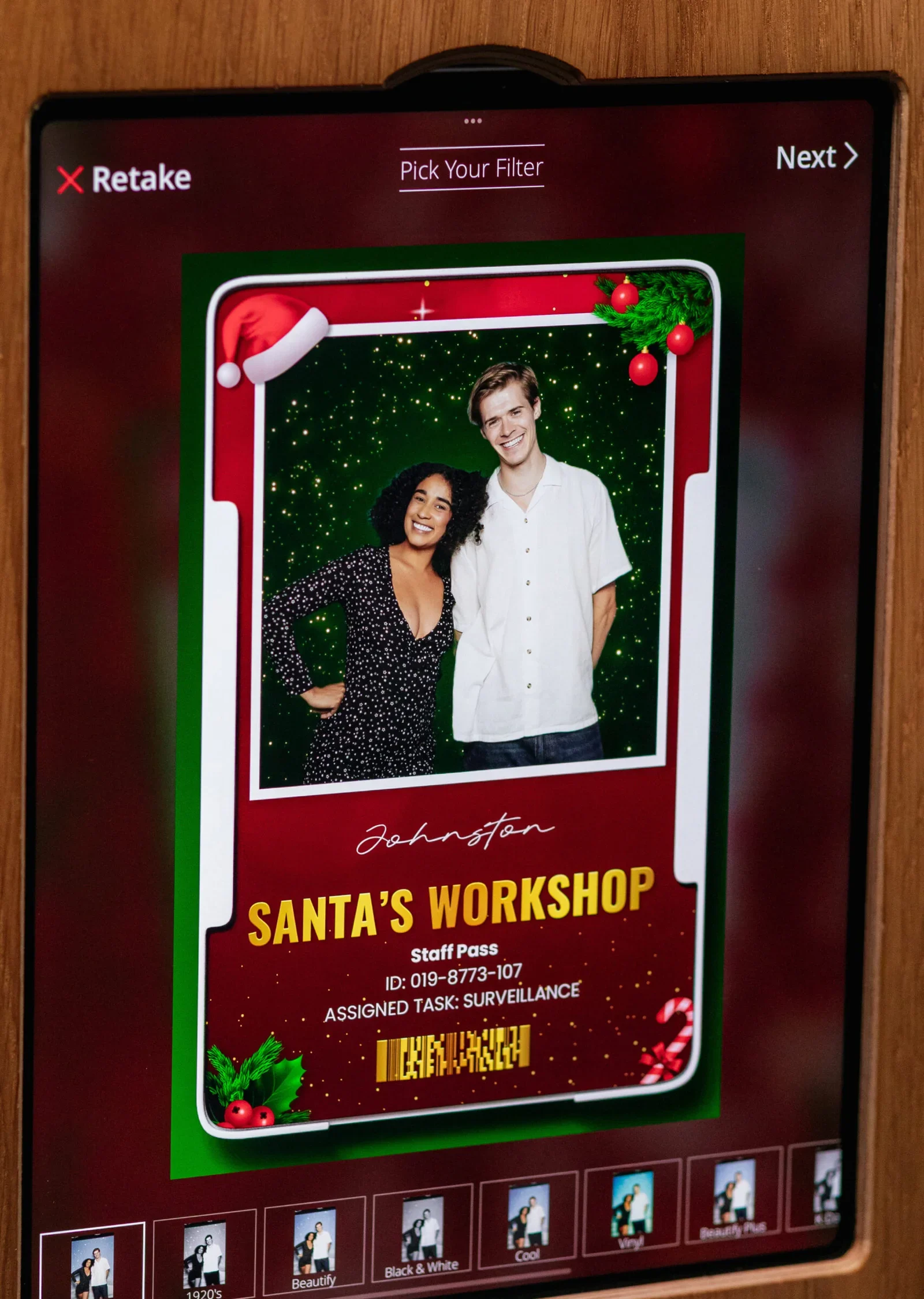 Photo booth screen showing a couple in a Santa's Workshop festive frame
