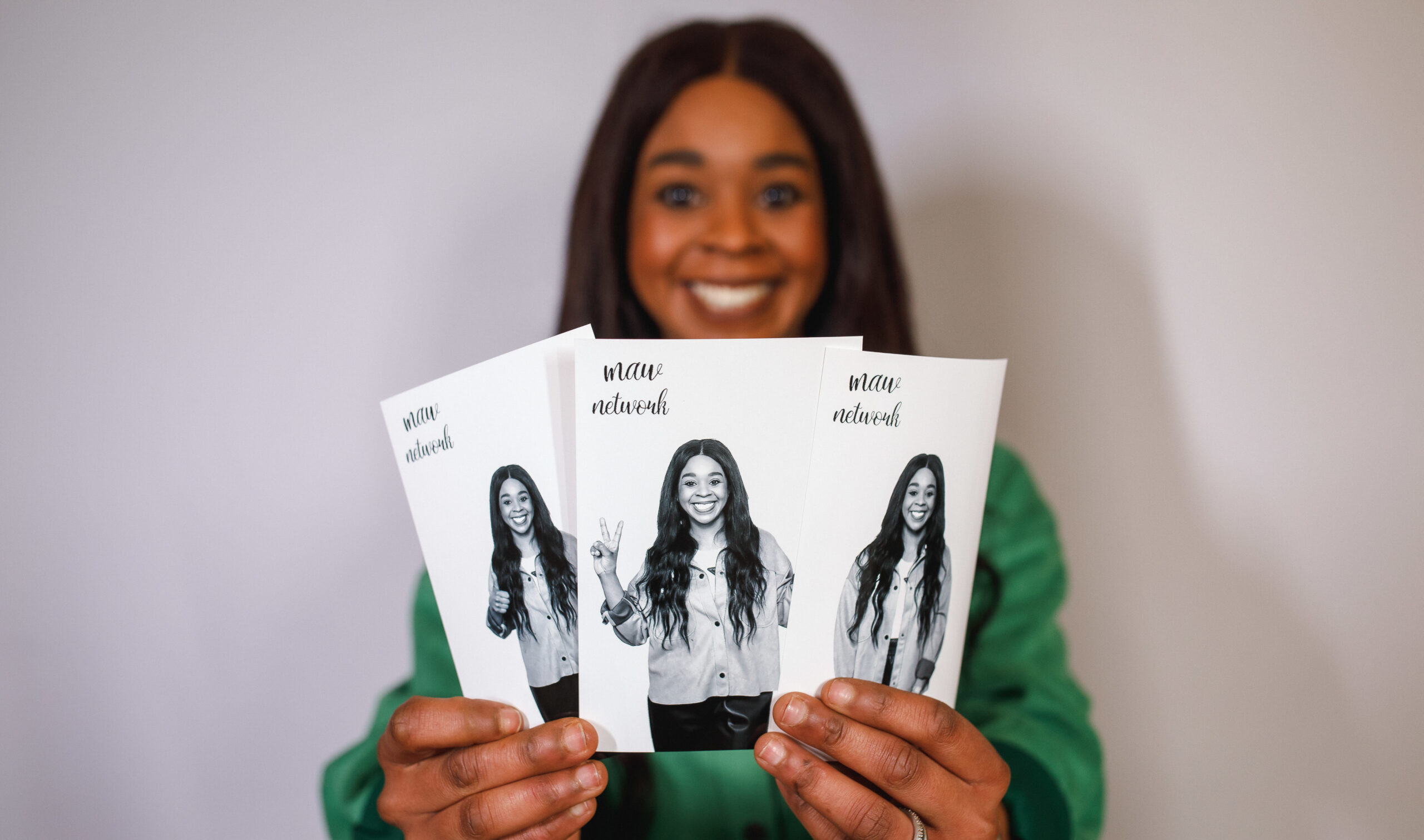 Woman smiling while holding three black and white photo booth prints