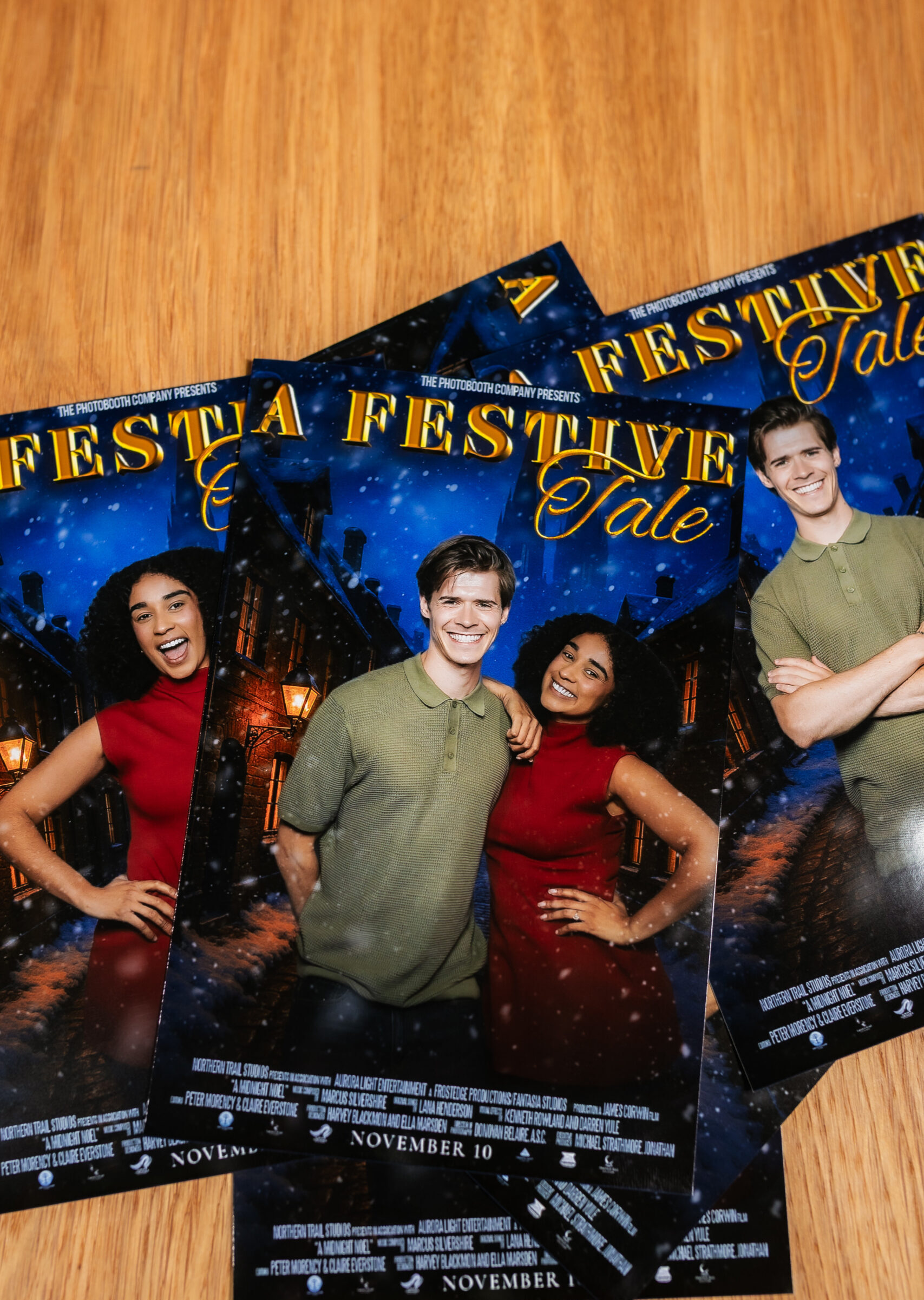 Printed festive photo booth cards fanned out on a wooden table