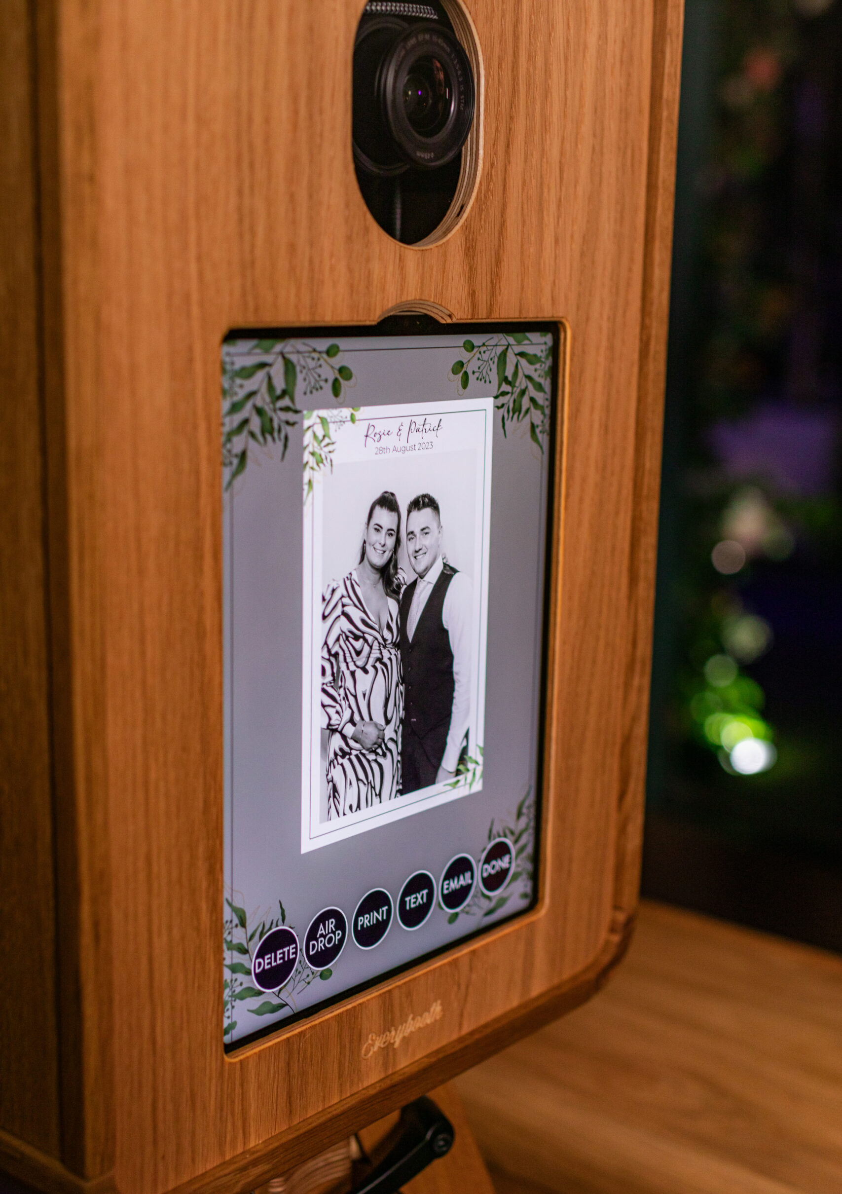 Wooden photo booth showing a couple's photo in a botanical frame